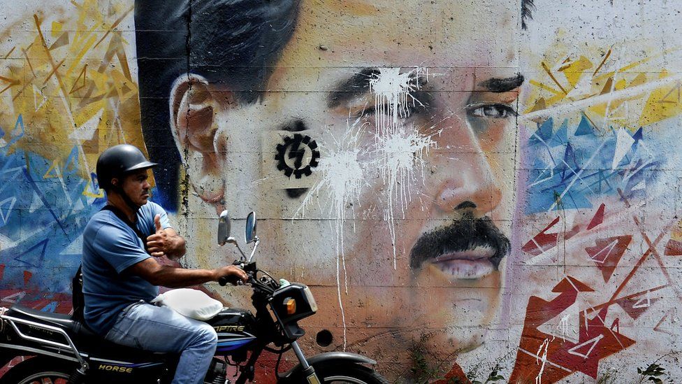 A motorcyclist passes by a graffiti depicting Venezuelan President Nicolas Maduro in Caracas on 17 April 2015.