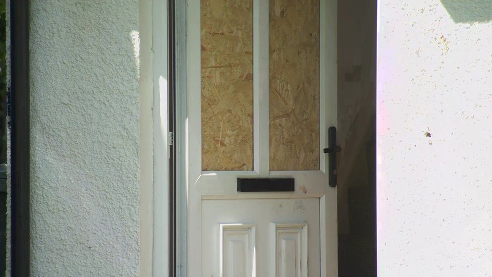 Boarded up window on door of attacked house