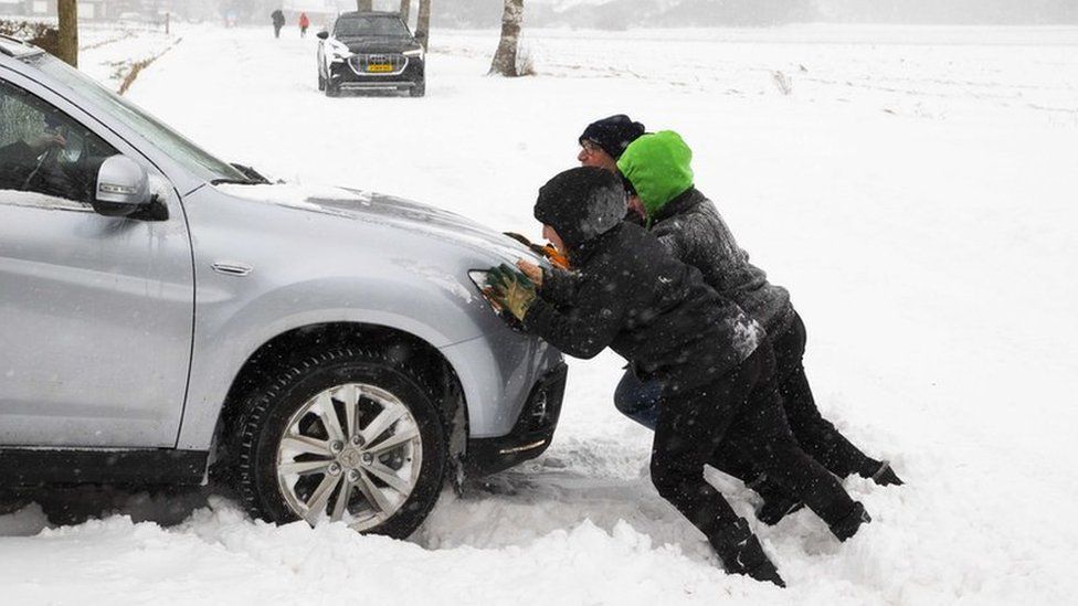 People push out a car that got stuck in a snow dune in Haarle, the Netherlands