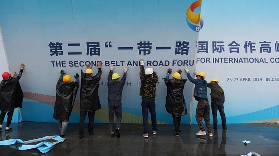 Workers take down a Belt and Road Forum panel outside the venue of the forum in Beijing on April 27, 2019