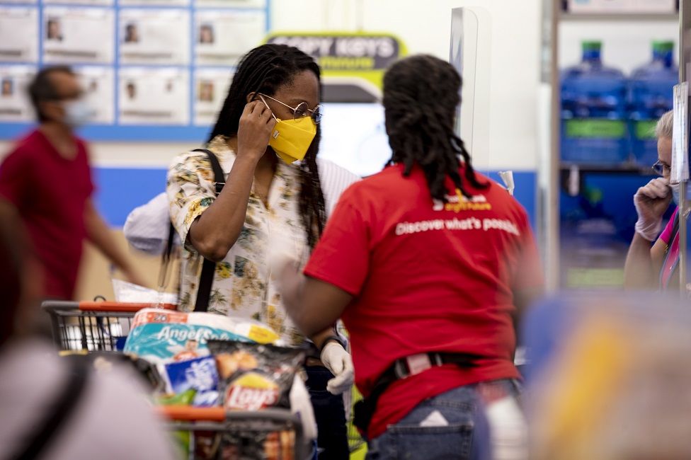 A Walmart shopper wears a face mask as protection against the coronavirus as she pays the cashier in a Walmart Supercenter in Burbank, California