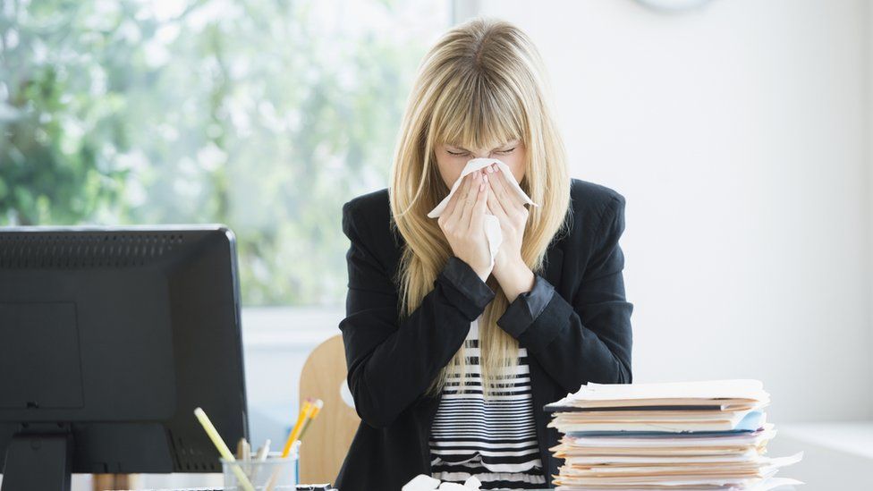 A women blows her nose in work