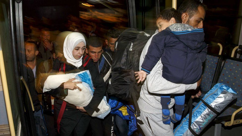 Syrian migrants board bus after arriving in port near Athens. 13 Sept 2015