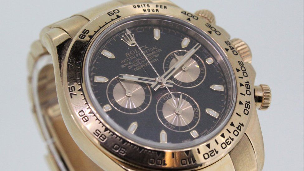 A black and rose gold rolex Daytona with a gold band
