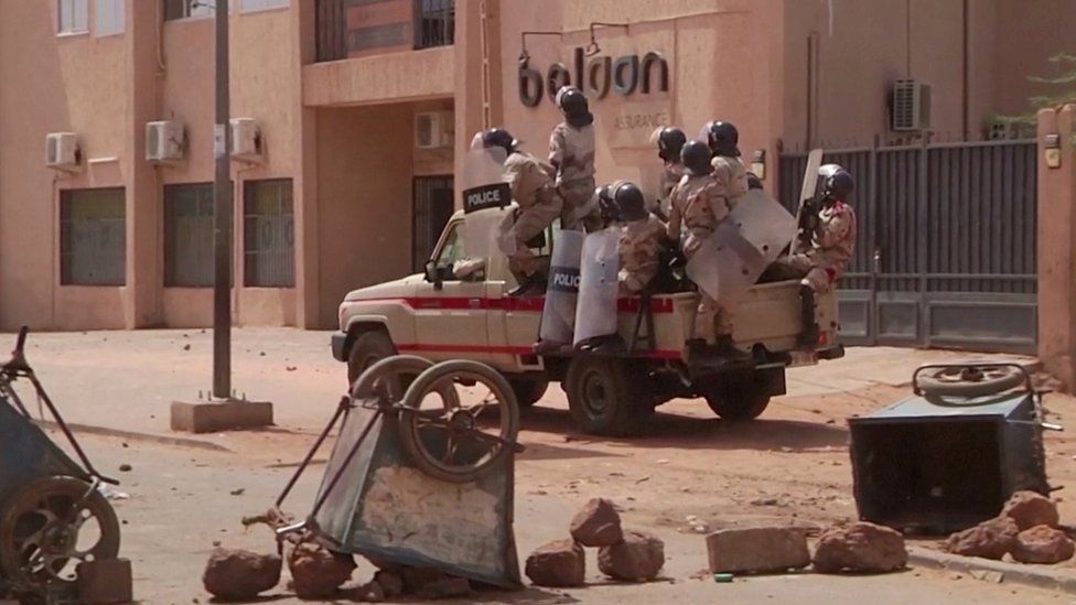 Riot policemen driving towards protesters at a makeshift checkpoint in Niamey, Niger