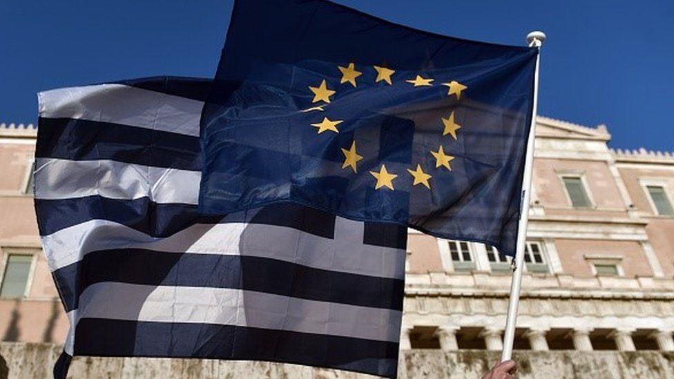 Greece and EU flags held aloft in front of the Greek parliament building