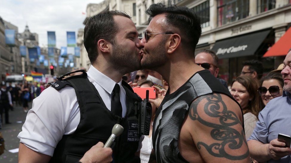 A policeman kissing his boyfriend at Pride after proposing to him