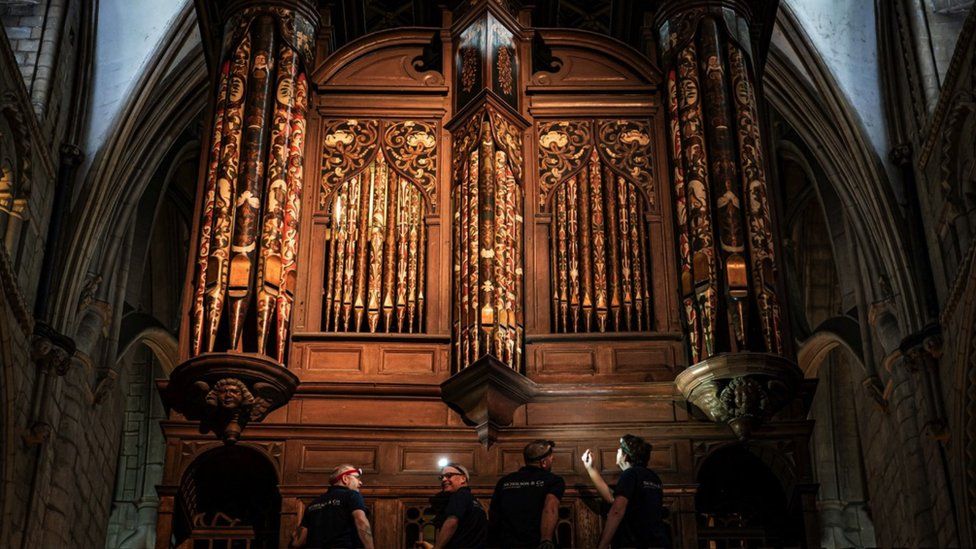 Image of four men working on the organ inside Gloucester Cathedral