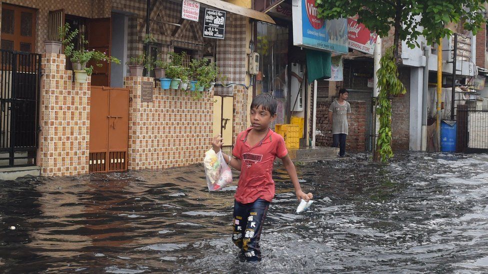 A boy wades along a flooded street after a monsoon rainfall in Ahmedabad on July 8, 2022.