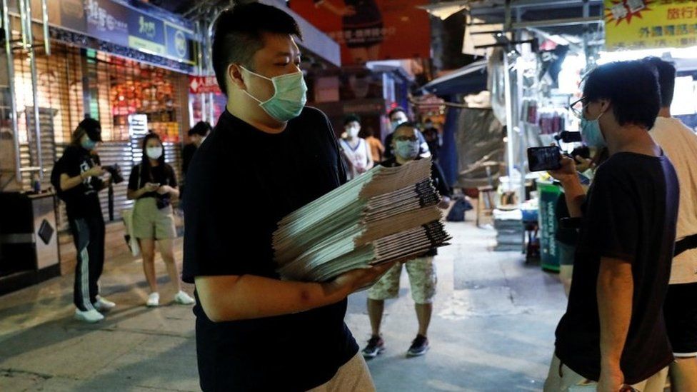 A man buys a pile of Apple Daily newspapres in Hong Kong