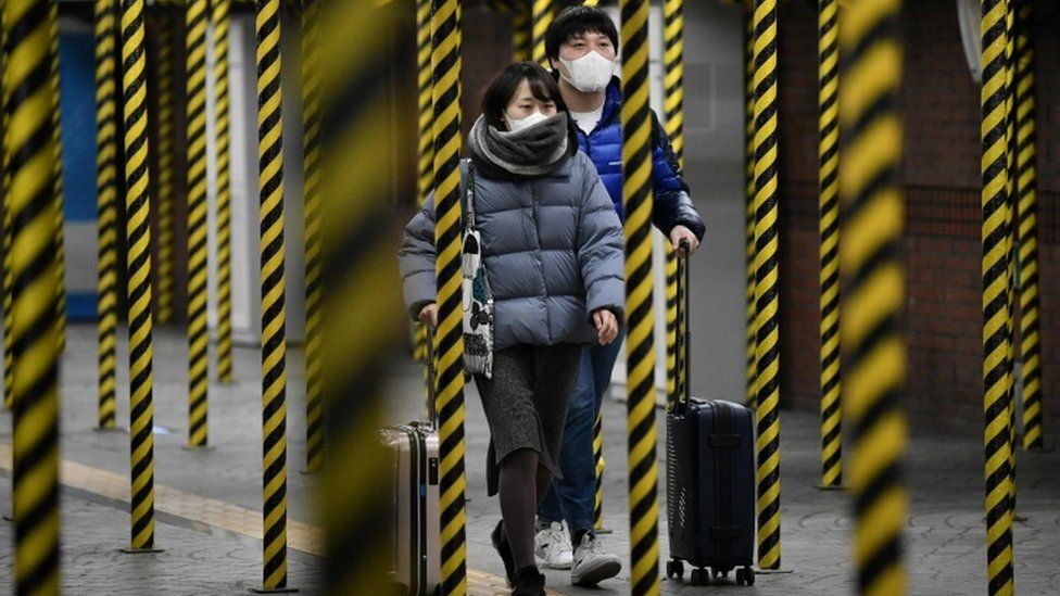 Passengers wearing face masks walk between columns at a subway station being renovated in Seoul
