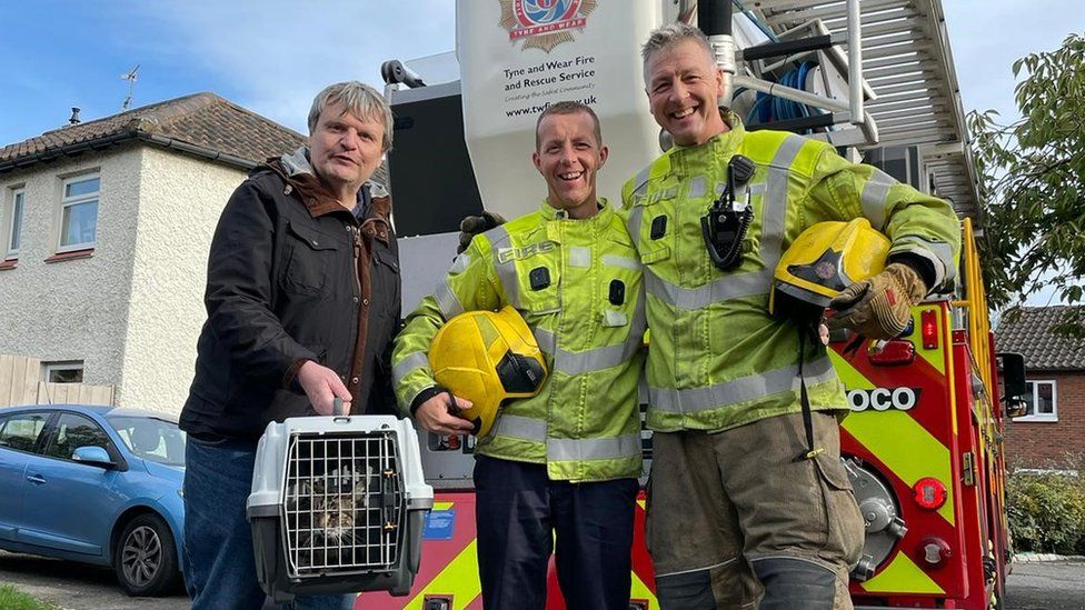 The rescued cat, the owner, Micky Longstaff and another fireman