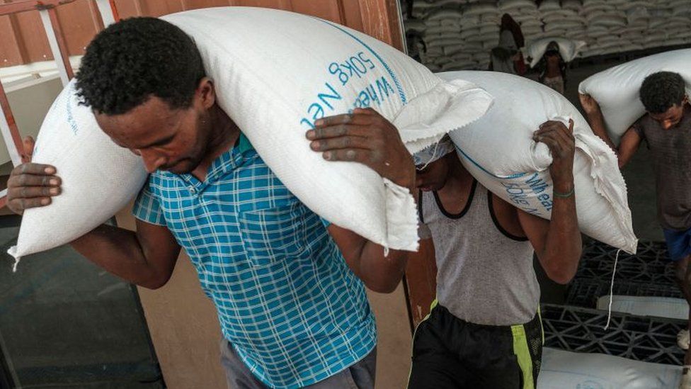 Workers carry sacks of grain in a warehouse of the World Food Programme (WFP) in the city of Abala, Ethiopia, on June 9, 2022.