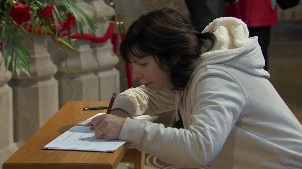 A woman signs the book of condolence for Pope Benedict XVI