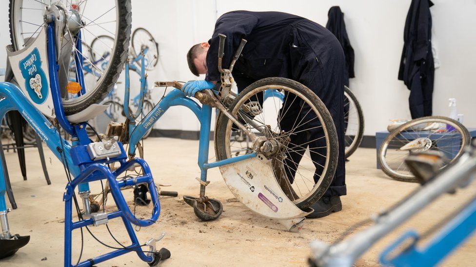 A prisoner repairs bikes in a workshop at category C prison HMP Five Wells in Wellingborough