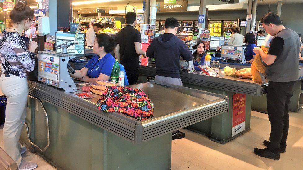 Shoppers pack their purchases into bags in a supermarket in Chile