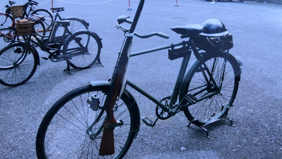 An old bike, with a rifle strapped to the handle bars.
