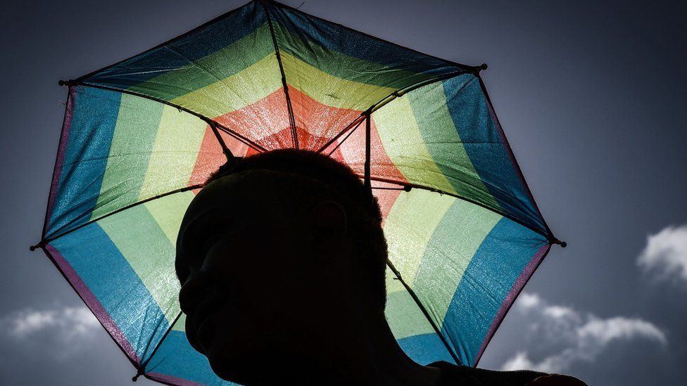 Член южноафриканского сообщества лесбиянок, геев, бисексуалов, трансгендеров и интерсексуалов (ЛГБТИ) держит зонтик в цветах радужного флага и принимает участие в ежегодном гей-параде в рамках Дурбанского фестиваля гордости, 29 июня 2019 года в Дурбан.