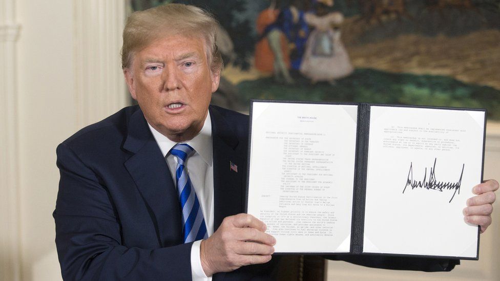Donald Trump holding aloft an order he signed withdrawing the US from the Iran nuclear deal