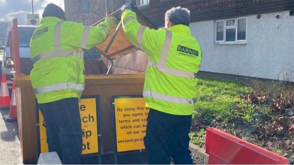 Two workers tip rubbish into the Barnet Community skip
