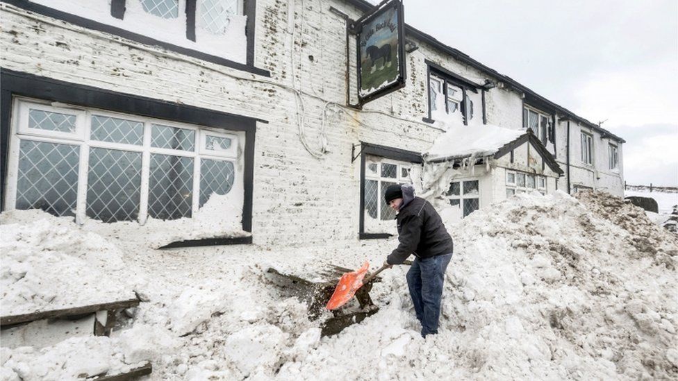 Landlord Angus Wharton clears snow outside the Ye Olde Black Ladd pub in Shaw, Greater Manchester.