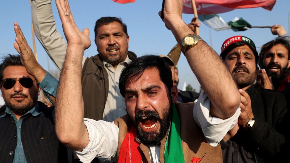 PTI supporters wearing red and green chanting against vote fraud at a protest on the Peshawar-Islamabad highway on 13 February
