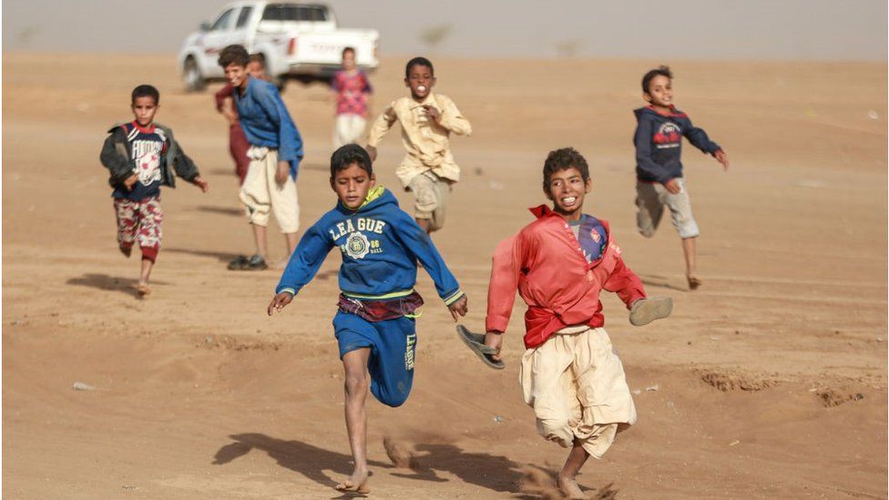 Children running the the sands of Kassala. One child can be seen laughing in the background.
