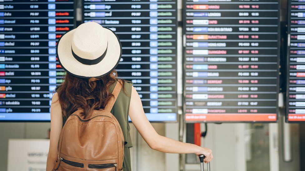 Женщина смотрит на табло вылета из аэропорта