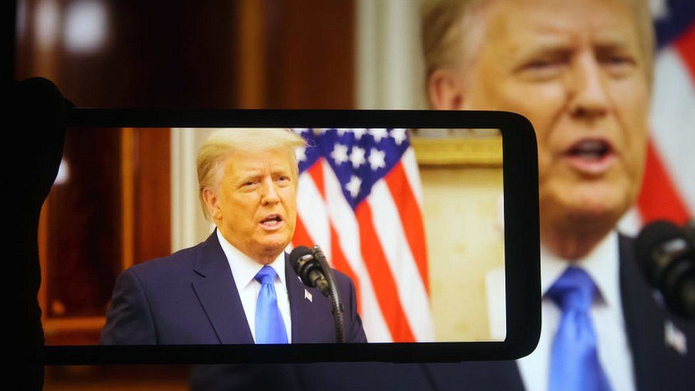 Изображение выступающего президента Трампа на мобильном телефоне