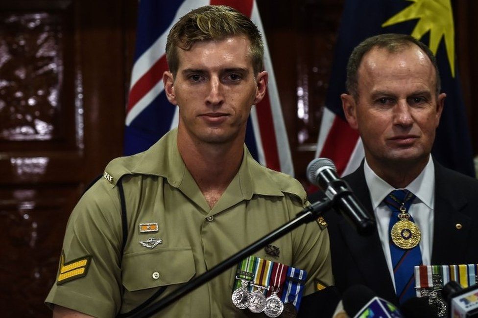 Australian military personnel Christopher Bowtell (L), whose late grandfather Robert Walter Bowtell's remains were sent back, attends a repatriation ceremony at the Royal Malaysian Airforce base in Subang