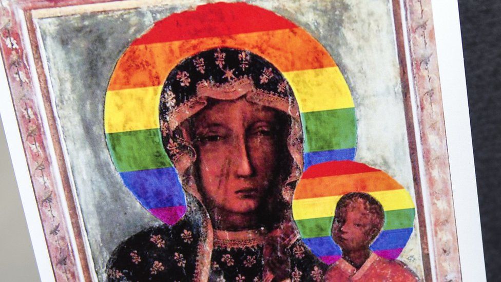 An old-fashioned painting of the Virgin Mary and child is seen printed on a piece of paper - but it has been modified so that the circular halo around both their heads, common to the Byzantine style, has been replaced with a rainbow