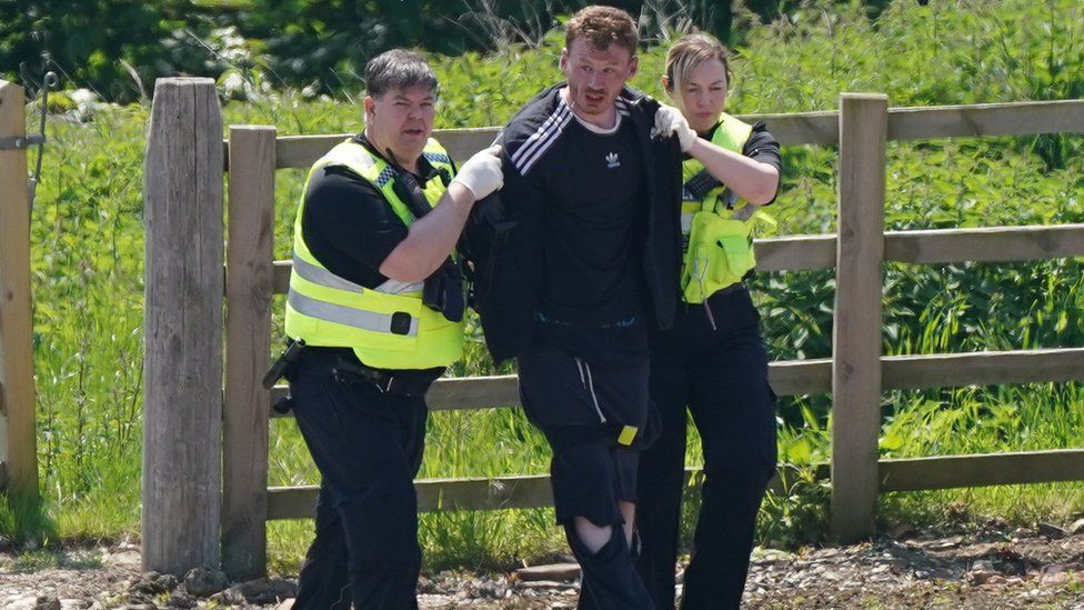 Two officers escort Daniel Boulton to a police van