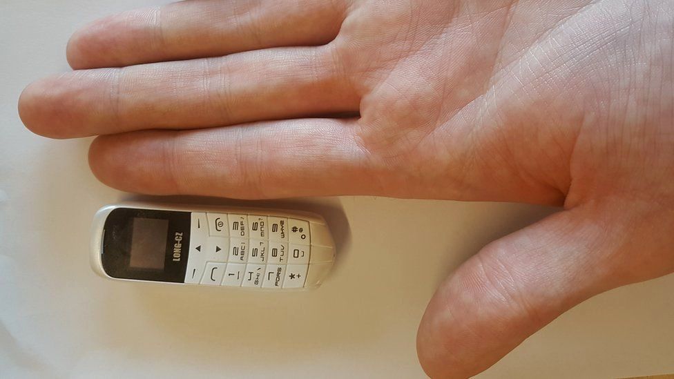 MoJ picture of a mini phone next to a hand