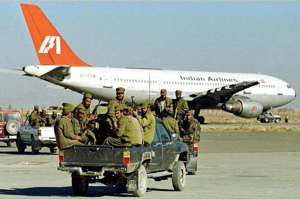 На этом снимке, сделанном 30 декабря 1999 года, спецназовцы исламского ополчения Талибана едут в задней части грузовика в сторону захваченного исламскими боевиками кахсмирских боевиков самолета авиакомпании Indian Airlines, который стоит на взлетной полосе в аэропорту Кандагара