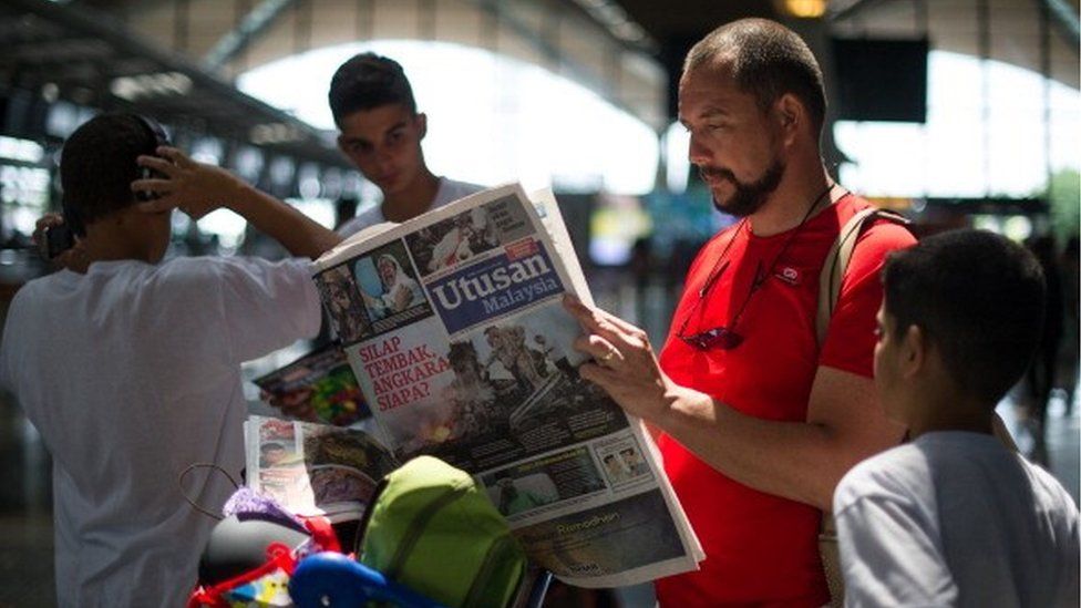 A tourist reads a Malaysian newspaper with reports about the Malaysia Airlines flight MH17 that crashed in eastern Ukraine, at Kuala Lumpur International Airport in Sepang, on July 19, 2014