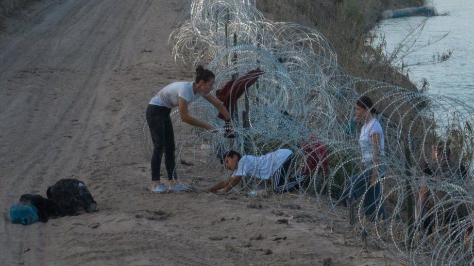 A migrant family attempts to navigate through concertina wire in Eagle Pass on 27 July