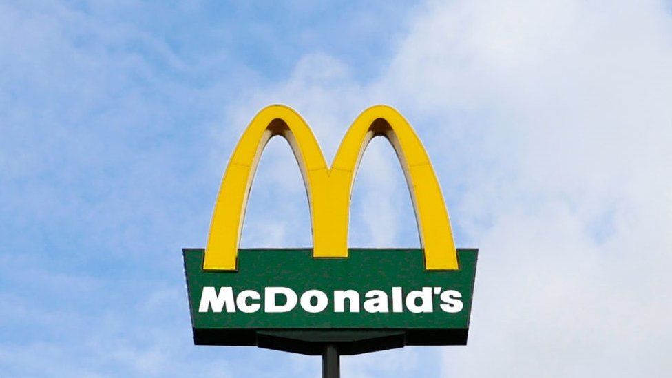 The McDonald's logo on a sign set against blue sky.