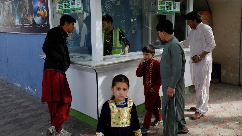 Маленькая девочка стоит перед билетной кассой в парке развлечений в Кабуле, Афганистан, 9 ноября 2022 г.
