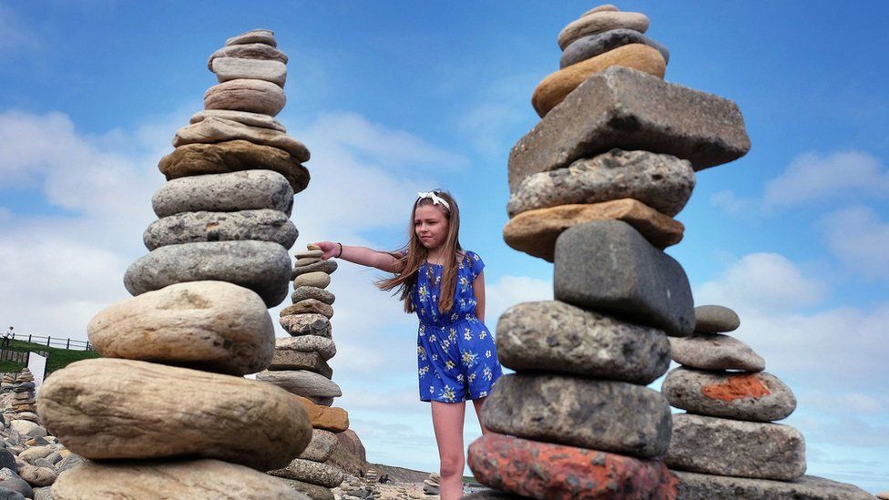 Girl adds pebbles to tower
