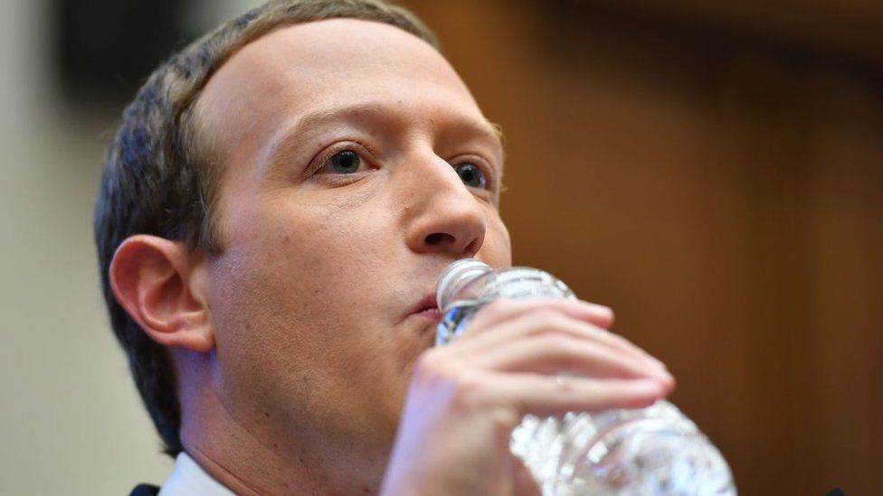 Председатель и главный исполнительный директор Facebook Марк Цукерберг пьет воду во время дачи показаний в Вашингтоне, округ Колумбия.