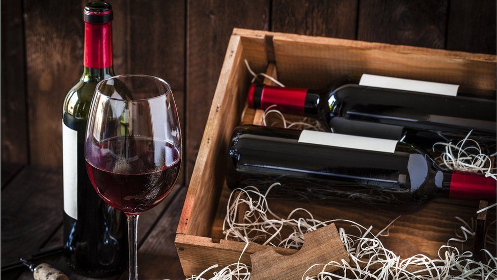 Glass of red win and bottles in a wooden box