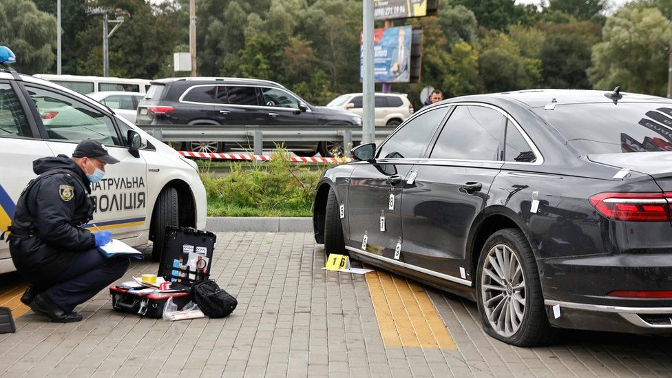 An investigator examines bullet holes in a car of presidential aide Serhiy Shefir following an assault outside Kyiv