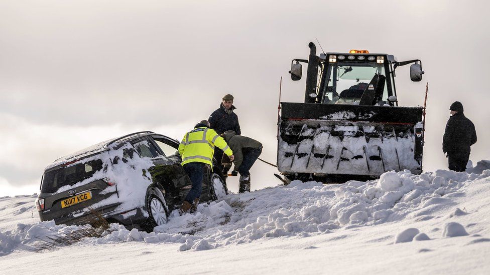 Car pulled from snow by tractor
