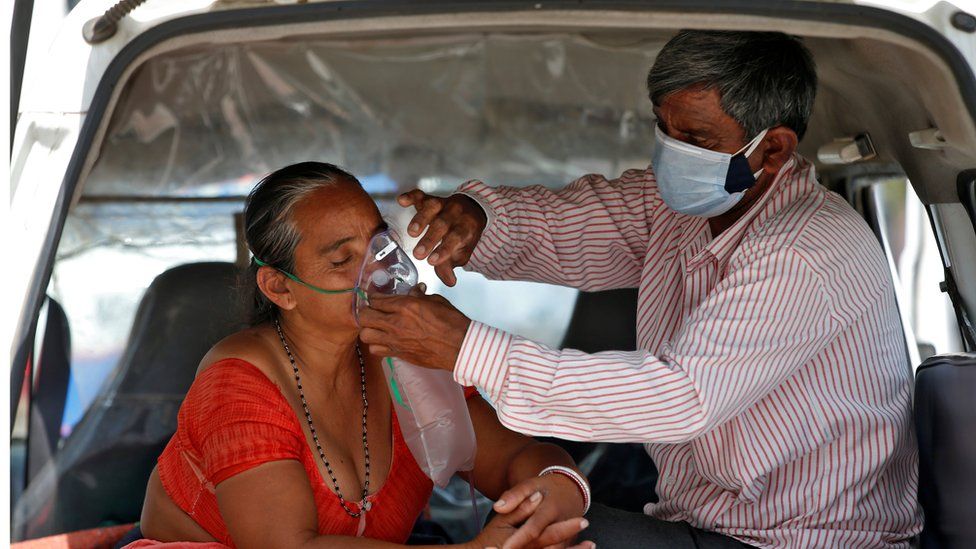 The husband of Nanduba Chavda adjusts his wife"s oxygen mask as they wait in a car to enter a COVID-19 hospital for treatment, amidst the spread of the coronavirus disease (COVID-19) in Ahmedabad, India, April 28, 2021.