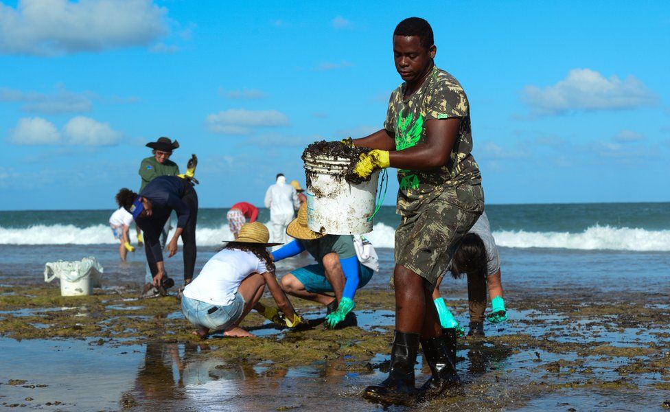 A man works to remove an oil spill on Muro Alto beach in Tamandare, Pernambuco