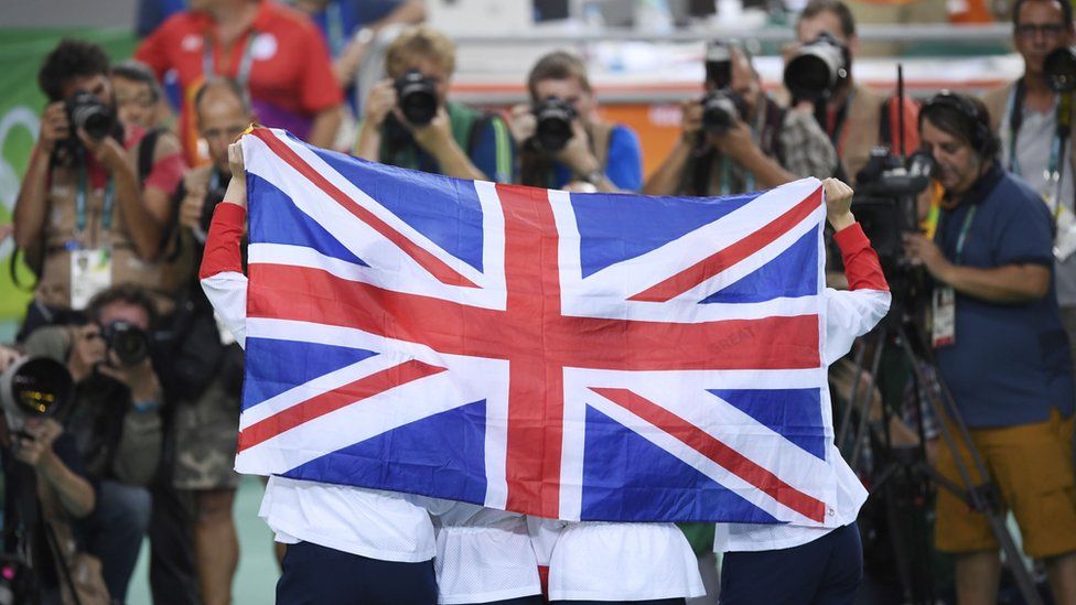 British Gold medallists hold up a flag as they pose on the podium after the women's Team Pursuit finals track cycling event at the Velodrome during the Rio 2016 Olympic Games