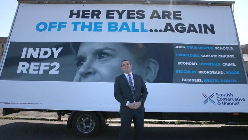 Douglas Ross poses in front of an ad van