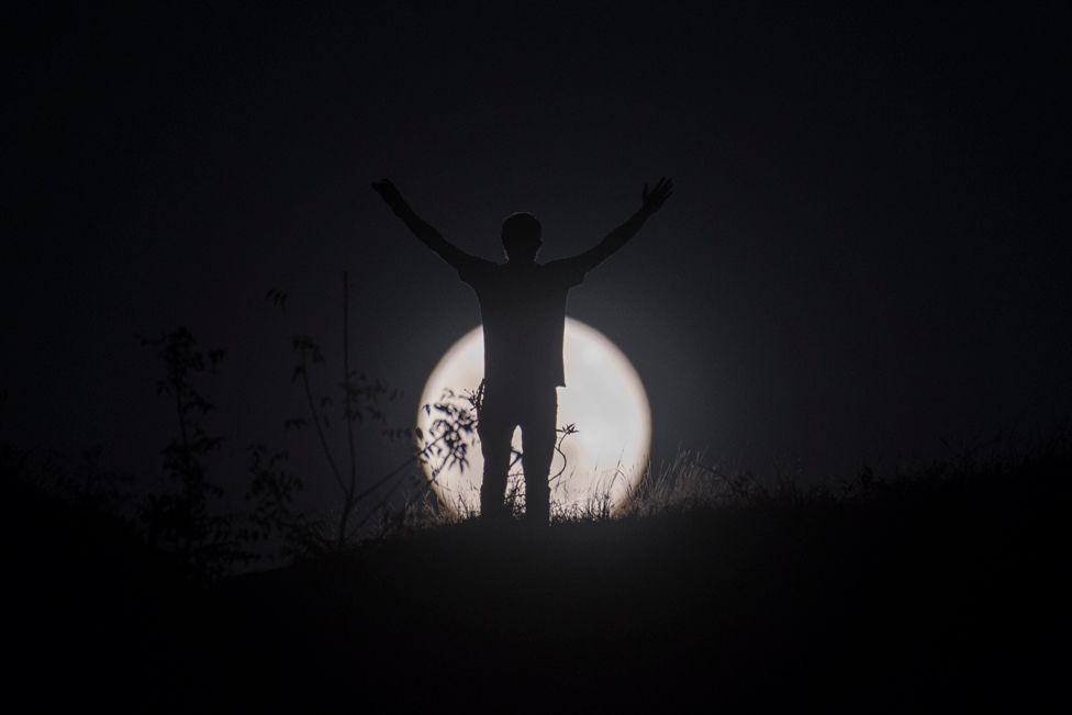 Silhouette of a man posing in front of the Wolf Moon, the first full moon of the year on 17 January 2022 in Mumbai, India