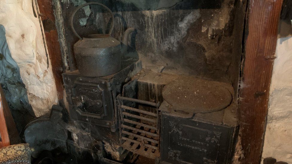 Very old and dusty, cobwebbed woodstoves with a kettle and frying pan on top