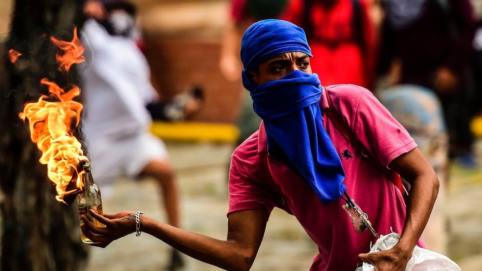 An opposition demonstrator prepares to throw a molotov cocktail during clashes with riot police in an anti-government protest in Caracas